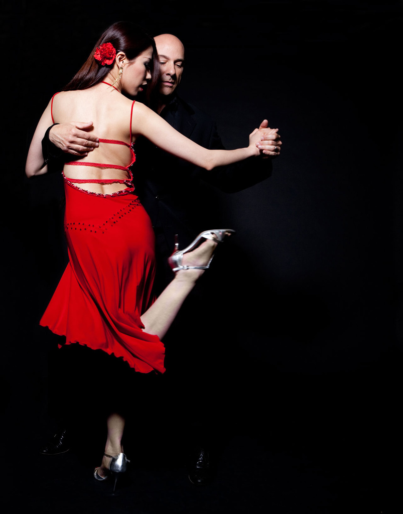 Tango couple with woman wearing red dress on black