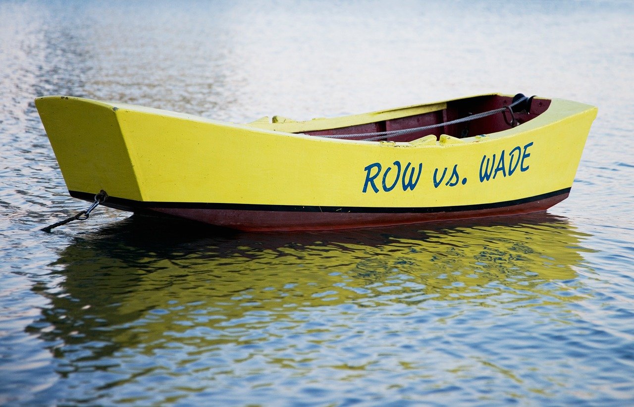 Wooden boat anchored with Row vs. Wade painted on it